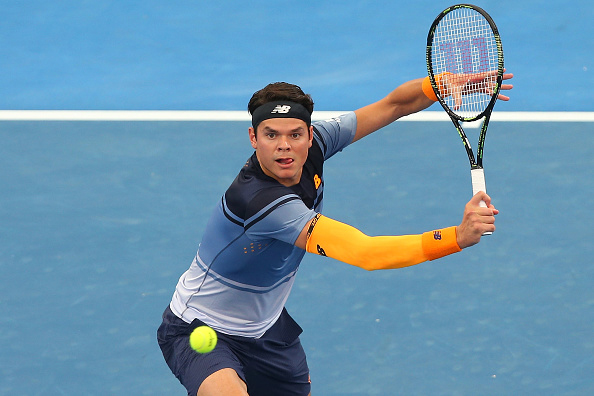 Milos Raonic plays a backhand volley in his New Balance outfit during his semi-final match at the Brisbane international.